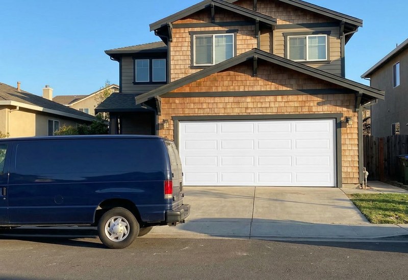 Newly installed white sectional garage door on a Bay Area craftsman home with branded service van in the driveway